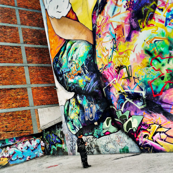 A Colombian man reads a message in front of a large graffiti artwork, created by artists named Jade & Vertigo Graffiti & MDCREW, in the center of Bogotá, Colombia.