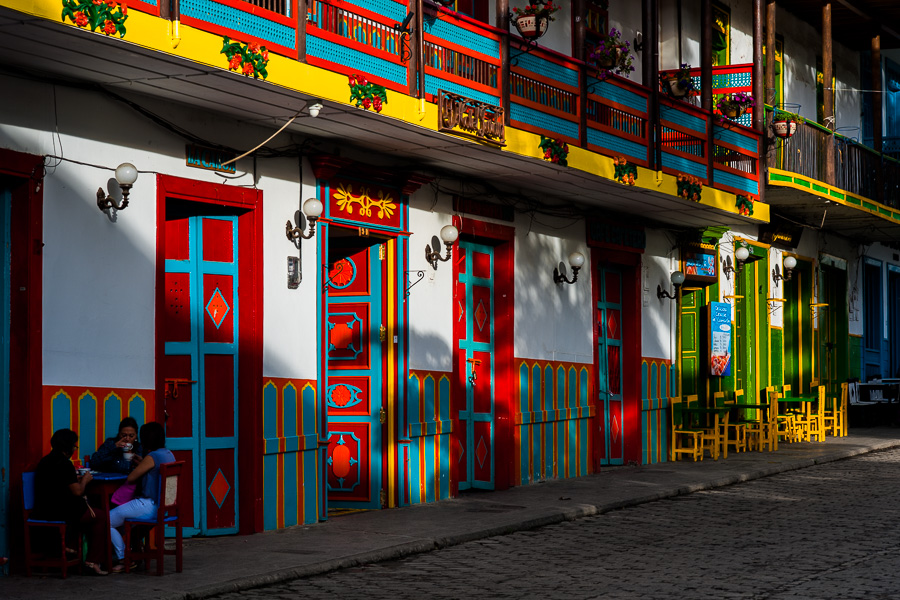 Colombian women sit in a coffee-shop in front of the brightly painted colonial house in Jardín, a village in the coffee region of Colombia.