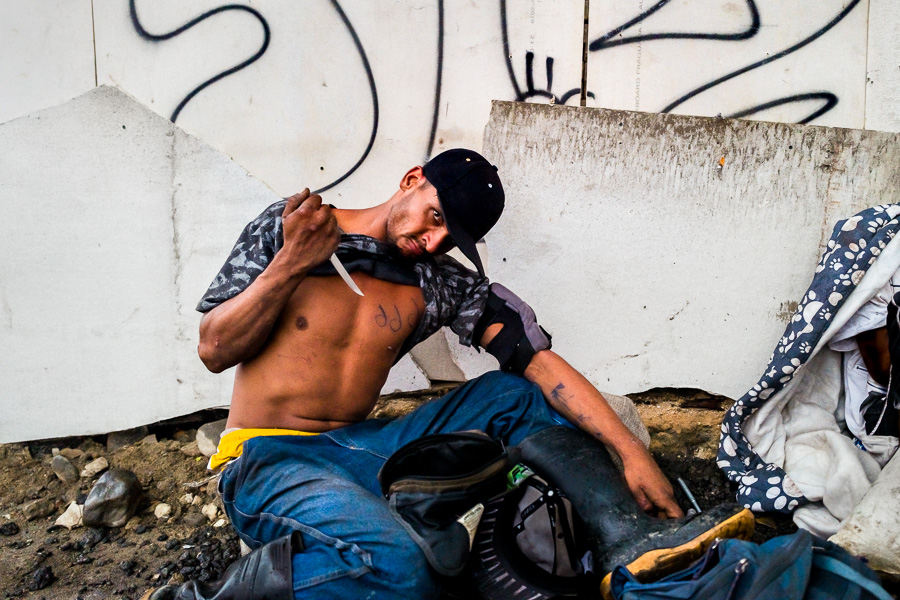 A young Colombian man makes a threat gesture with the knife while hanging around in the center of Medellín, Colombia.