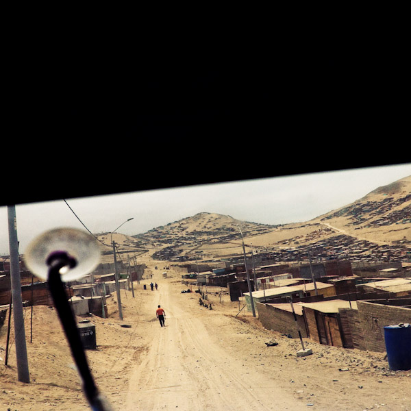 A sprawling settlement of houses, cut by an unpaved road, is seen on the dusty hillsides of Pachacútec, a desert shantytown in Lima, Peru.