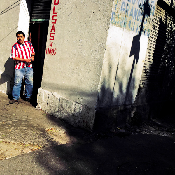 A Mexican man watches the street from the corner during a sunny morning in Buenavista, a neighborhood in Mexico City, Mexico.
