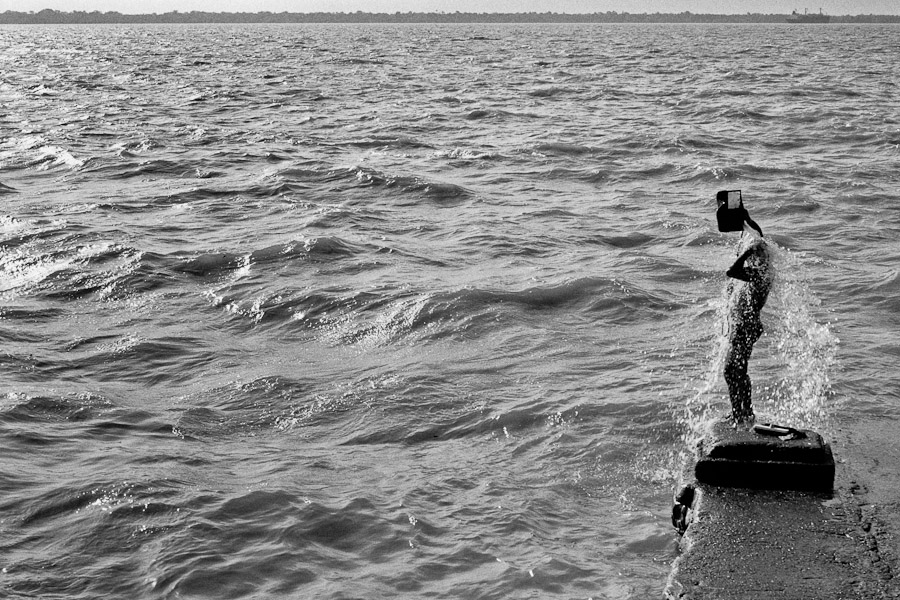 A man washing himself by the water from the Amazon river, in the port of Belém.