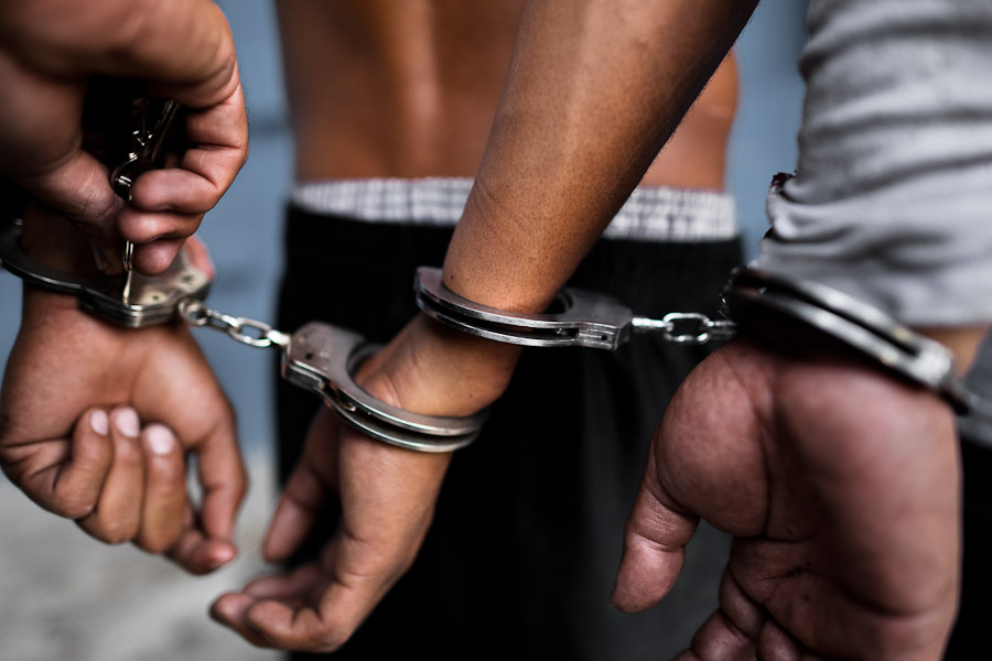 Alleged Mara gang members are handcuffed by a police officer from the special Anti-gang unit at the detention center in San Salvador, El Salvador.