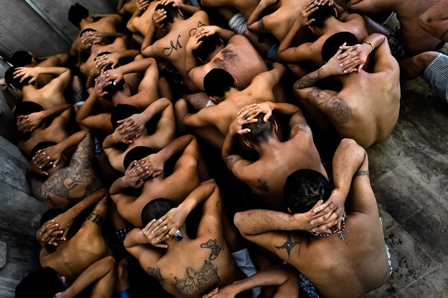 Mara gang members, having hands behind theirs heads and sitting on the floor, pass through a random search at the detention center in San Salvador, El Salvador.