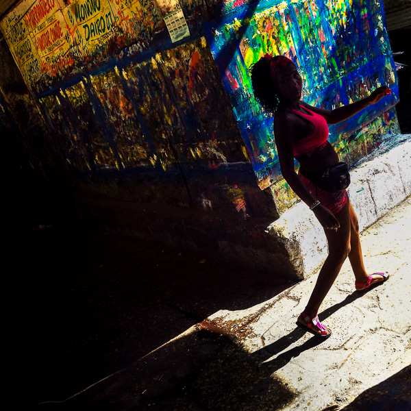 A Colombian woman walks along the wall, covered by the Champeta music posters scraps, at the market of Bazurto in Cartagena, Colombia.