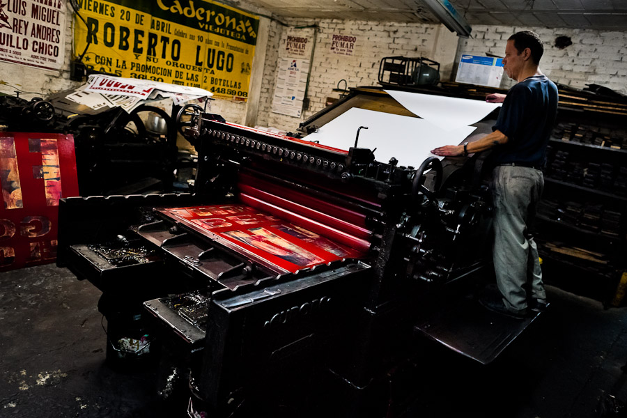 A Colombian master printer works on the ancient letterpress machine in the print shop in Cali, Colombia.