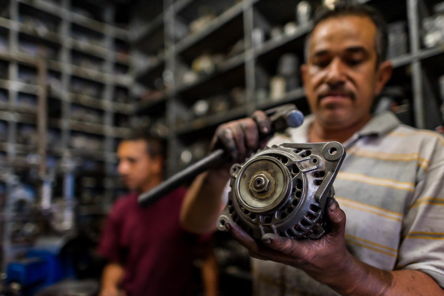 A Colombian car mechanic works on an alternator in a car repair shop in Barrio Triste, Medellín, Colombia.