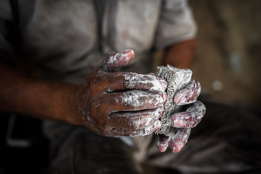 A Colombian car mechanic cleans his greasy hands with a soap and brush after finishing the daily work in Barrio Triste, Medellín, Colombia.