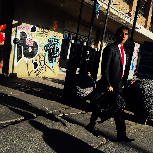 A Mexican office worker walks around the street corner during a sunny morning in Mexico City, Mexico.