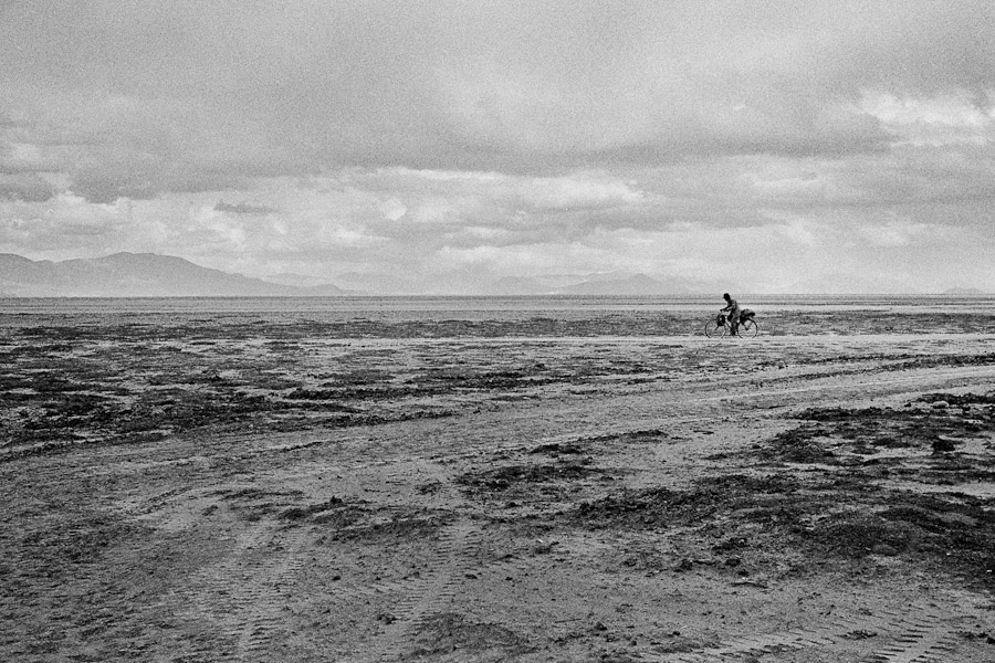 A Bolivian peasant rides a bicycle on a vast mountain plateau close to Oruro, Bolivia.