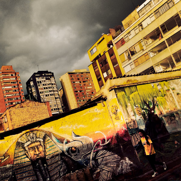 A Colombian girl walks in front of a mural artwork in Germania, Bogotá, Colombia.