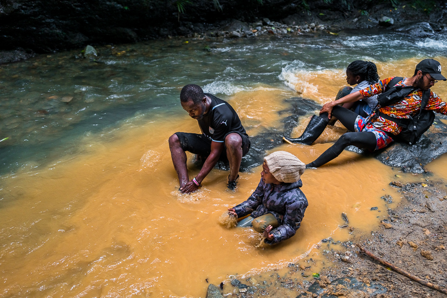 A Nigerian family of migrants washes the mud off their feet after passing through a muddy trail in the wild and dangerous jungle of the Darién Gap between Colombia and Panamá.