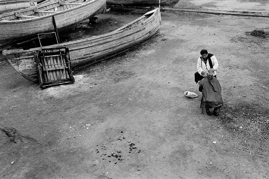 A barber shaving an old fisherman at caleta (a service yard) in the port of Coquimbo, Chile.