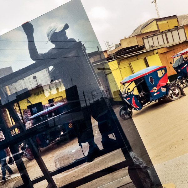 A Peruvian worker unloads a large window glass from a truck on the street of Pachacútec, a desert shantytown in Lima, Peru.