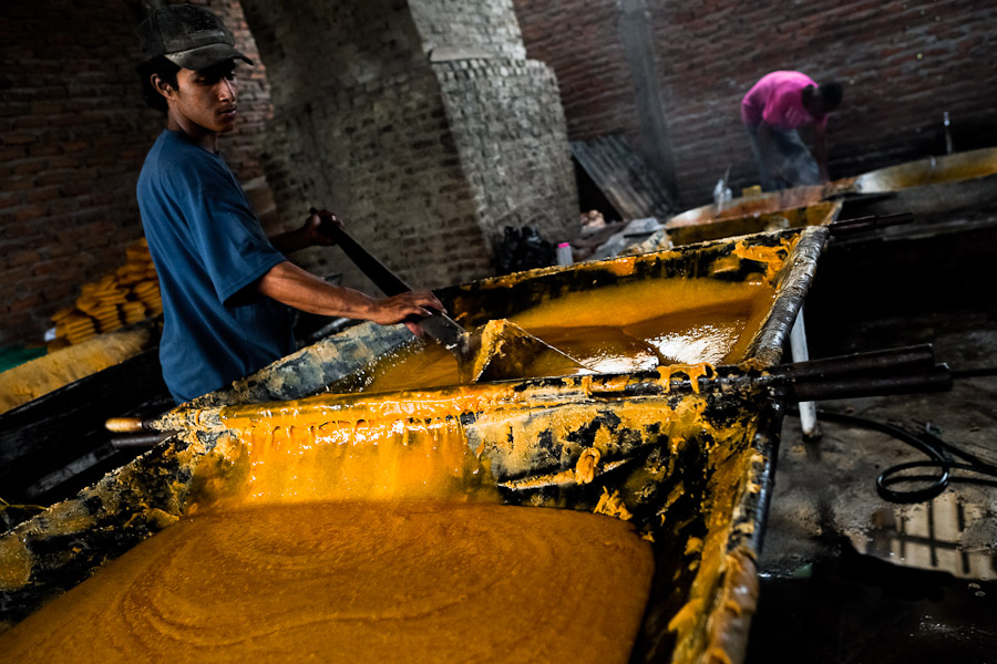 A Colombian peasant mixes a hot mass of sugar cane juice during the processing of panela in a rural sugar cane mill (trapiche) in Valle del Cauca, Colombia.