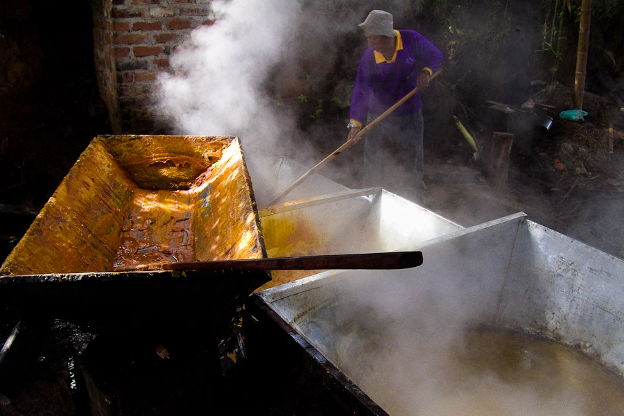 A Colombian peasant scoops up hot sugar cane juice in a cooking pot during the processing of panela in a rural sugar cane mill (trapiche) in San Agustín, Colombia.
