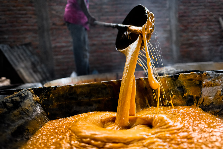 A Colombian peasant pours hot sugar cane juice into a cooking pot during the processing of panela in a rural sugar cane mill (trapiche) in Valle del Cauca, Colombia.