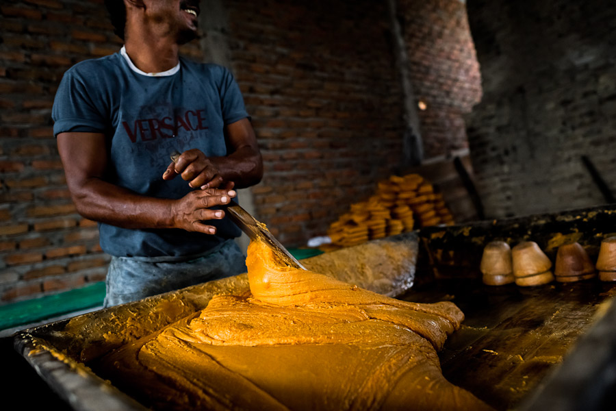 A Colombian peasant mixes a hot mass of sugar cane juice during the processing of panela in a rural sugar cane mill (trapiche) in Valle del Cauca, Colombia.