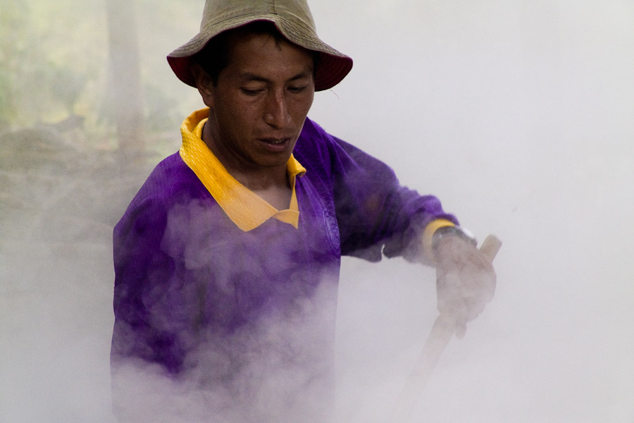 A Colombian peasant works in the smoke of boiling sugar cane juice during the processing of panela in a rural sugar cane mill (trapiche) in San Agustín, Colombia.