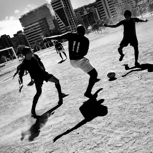 Ecuadorian men play football on a dirt football pitch in Parque La Carolina, a park in the central business district of Quito, Ecuador.