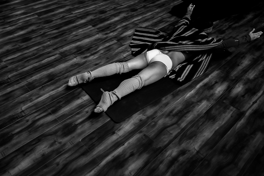 A young Colombian pole dancer warm ups on the floor for a pole dance training session in a gym in Bogotá, Colombia.