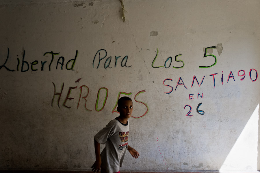 A Cuban boy runs in front of the concrete wall with a propaganda writing in Abel Santamaría, a public housing suburb of Santiago de Cuba, Cuba.