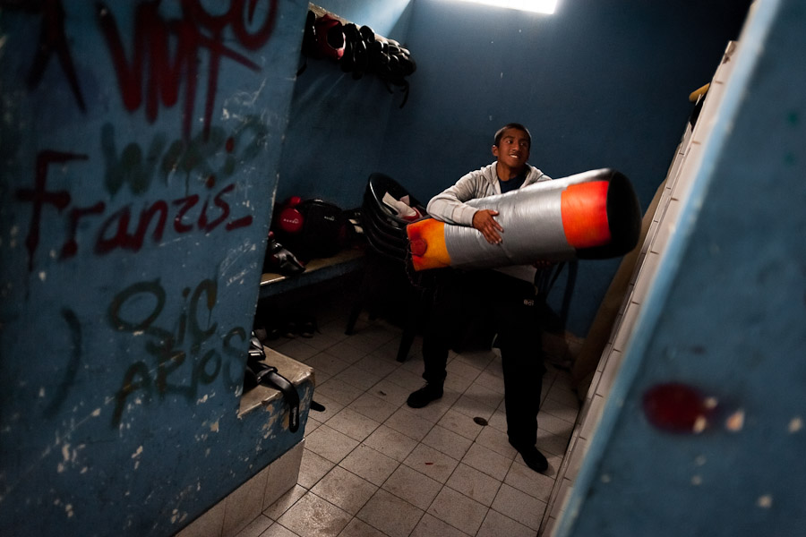 A Peruvian youth carries a punching bag from the changing room of the Boxeo VMT boxing club in an outdoor gym in Lima, Peru.