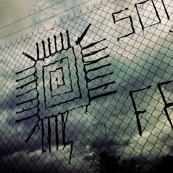 A quadrate spiral sign made of ribbons is seen on the chain link fence on the street of Quito, Ecuador.