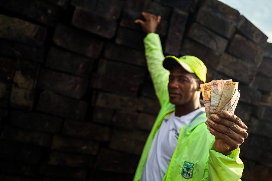 An Afro-Colombian wood reseller holds banknotes while selling rough sawn timbers in the port of Turbo, Colombia.