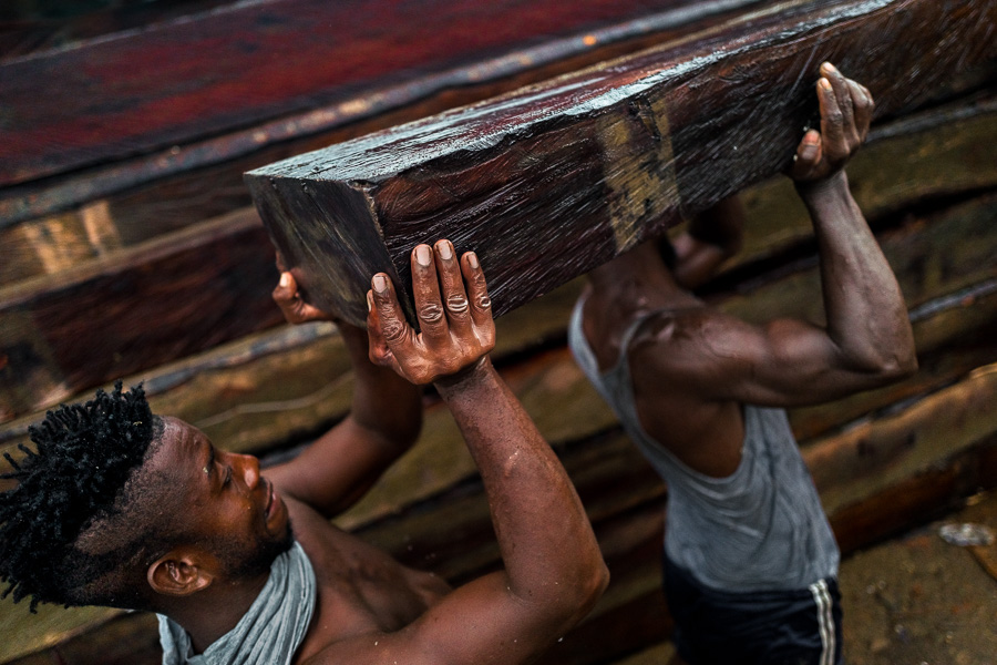 Afro-Colombian carriers lift a rough sawn timber during wood transportation in the port of Turbo, Colombia.