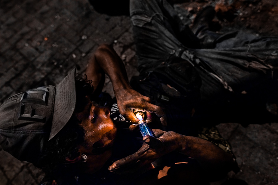 A young colombian man smokes “bazuco” (a raw cocaine paste) during the night in the street of Medellín, Colombia.