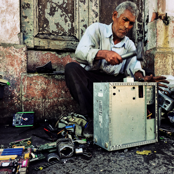 A Salvadoran recycler dismantles an old desktop computer to obtain valuable components and metals on the street of San Salvador, El Salvador.