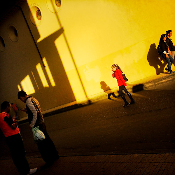 A Colombian woman, wearing a red coat, crosses the street in front of a church in Bogotá, Colombia.