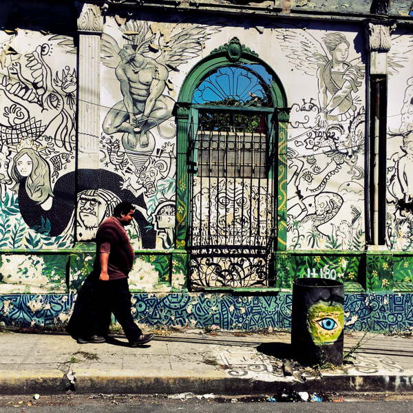 A Salvadoran man walks in front of a ruined house with Spanish colonial architecture elements, painted over by a local artist, in the center of San Salvador, El Salvador.