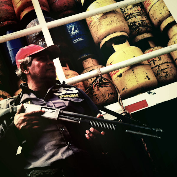 A Salvadorean private security guard holds a shotgun during the unload of gas cylinders on the street of San Salvador, El Salvador.