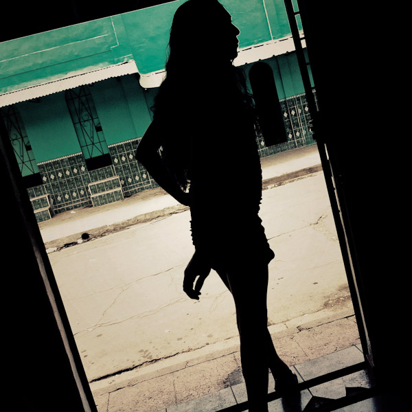 A Salvadorean sex worker, standing in the bar door, look out for clients in the street of San Salvador, El Salvador.