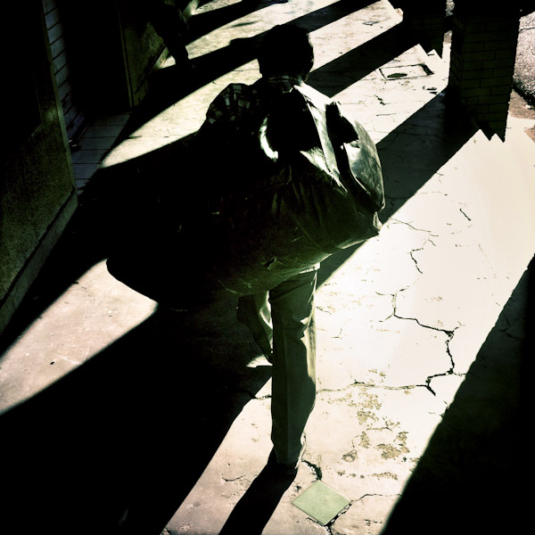 A Salvadorean street vendor, carrying a heavy load of goods, walks through a colonial cloister in the center of San Salvador, El Salvador.