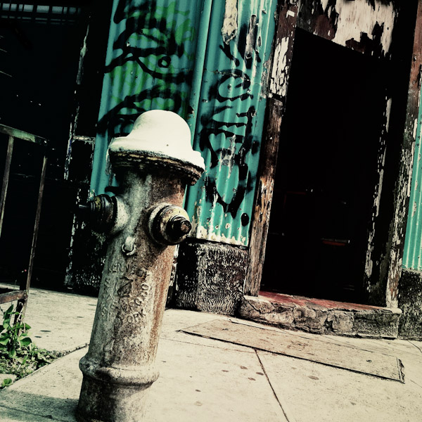 A water hydrant seen in front of a house made of wood and sheet metal on the street of San Salvador, El Salvador.