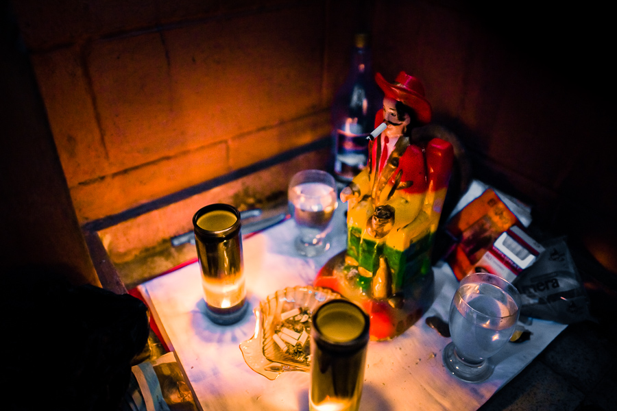 An altar of San Simón (a patron saint of sex workers), surrounded by offerings, is seen placed underneath the bar in a sex club in San Salvador, El Salvador.