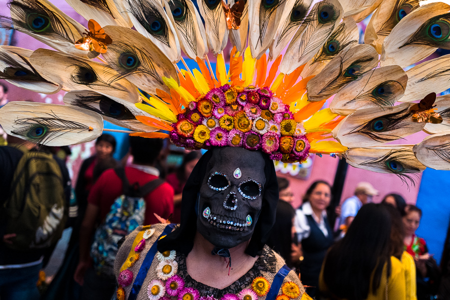 A Mexican woman, wearing a scull mask with a feather headdress, performs on the street during the Day of the Dead celebrations in Oaxaca, Mexico.