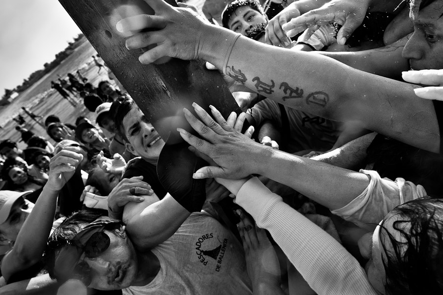 Catholic believers try to touch the cross to wash off their sins during the annual Semana Santa celebration.