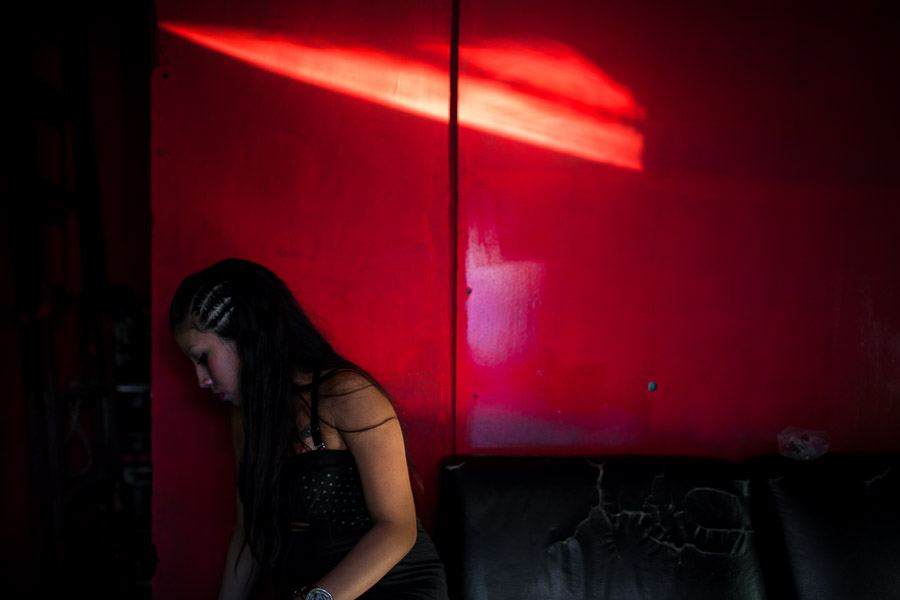 A Salvadoran sex worker sits in front of a room where her sexual services are offered to clients in San Salvador, El Salvador.