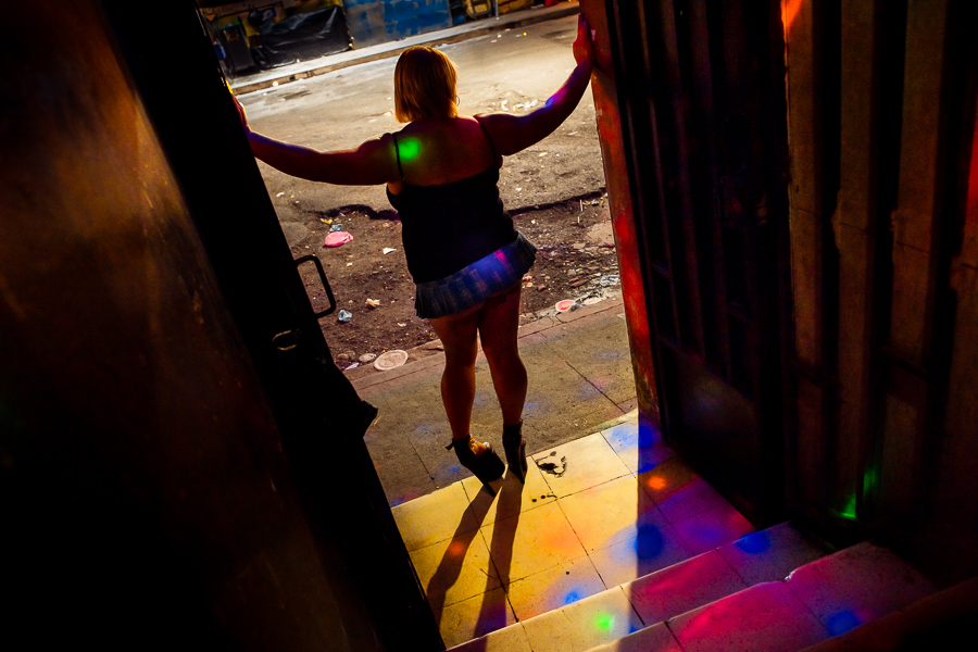 A Salvadoran sex worker, standing in the door, attracts customers to a sex club in San Salvador, El Salvador.