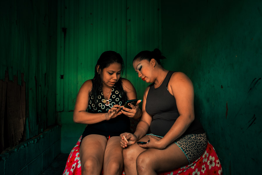 Salvadoran sex workers chat on the phone while waiting for clients in a room of a street sex bar in San Salvador, El Salvador.
