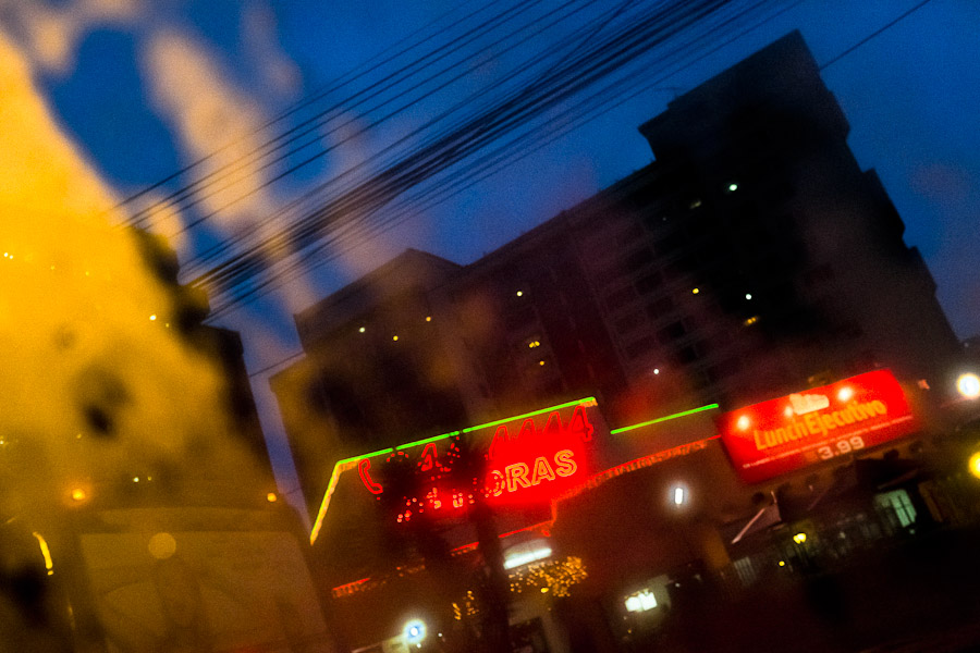 Shining city lights seen through a rainy car window during the twilight in Quito, Ecuador.