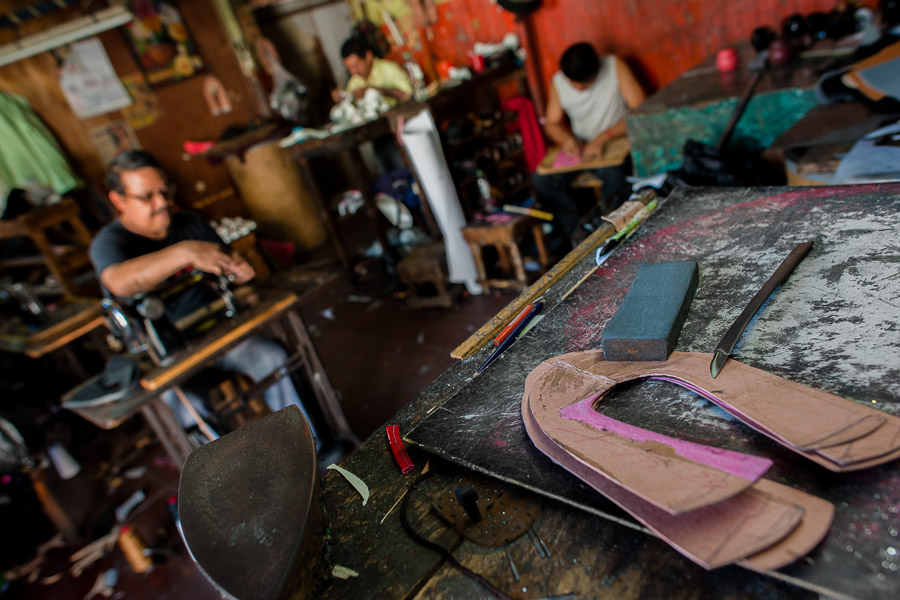Shoe upper patterns and a cutting tool are seen lying on the workbench in a shoe making workshop in San Salvador, El Salvador.