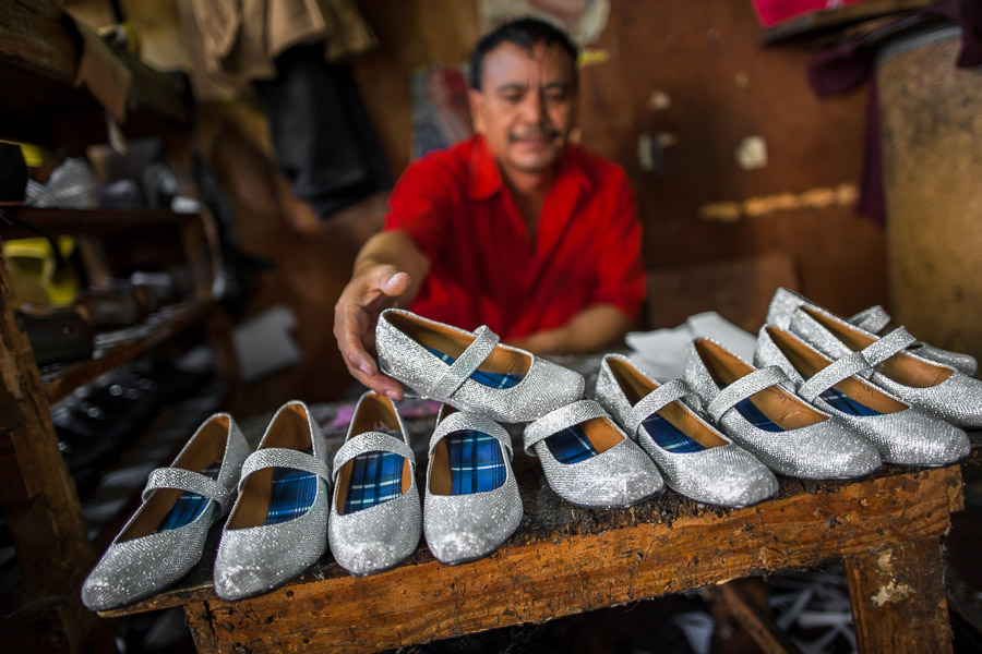 A Salvadoran shoemaker displays newly made pairs of girl’s silver glitter shoes on the workbench in a shoe making workshop in San Salvador, El Salvador.