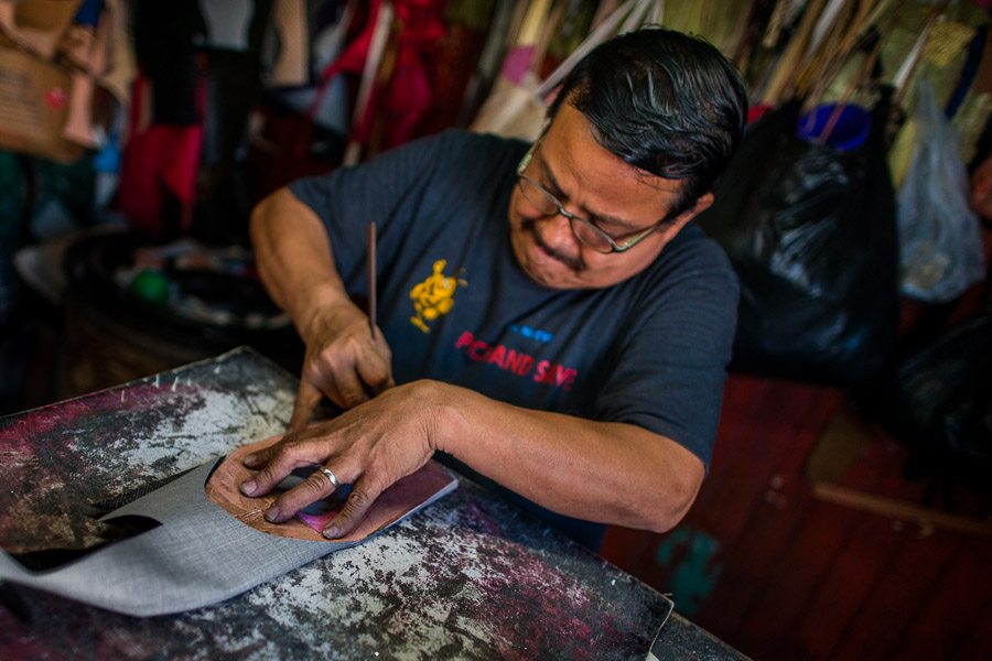 A Salvadoran shoemaker cuts a shoe upper from a fiber sheet on the workbench in a shoe making workshop in San Salvador, El Salvador.