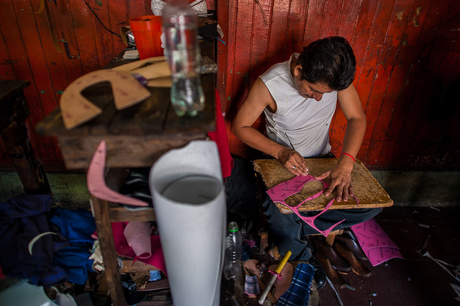 A Salvadoran shoemaker cuts an insole from a fiber insole sheet on the wooden desk in a shoe making workshop in San Salvador, El Salvador.