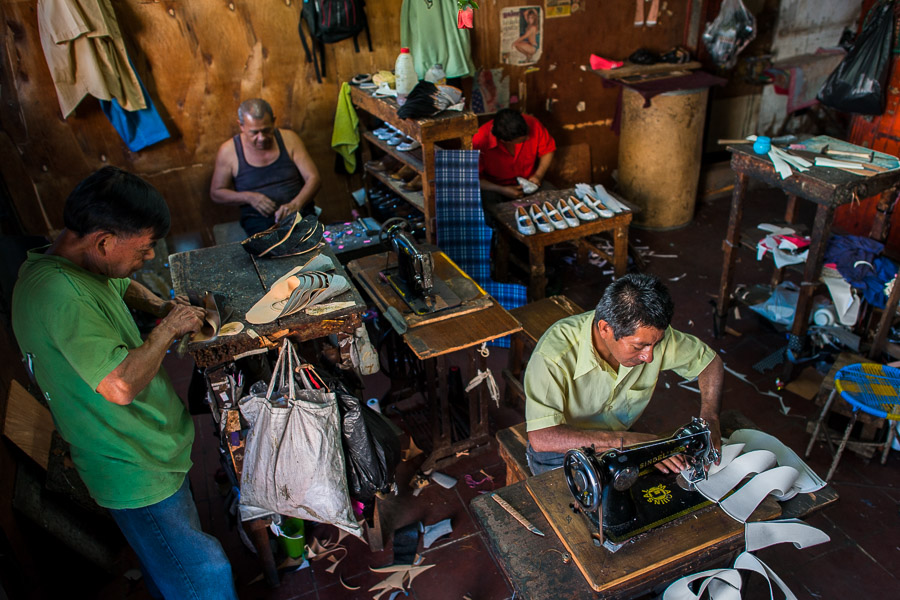 Salvadoran shoemakers work on new shoes, each one focused on a different stage of the production process, in a small shoe making workshop in San Salvador, El Salvador.